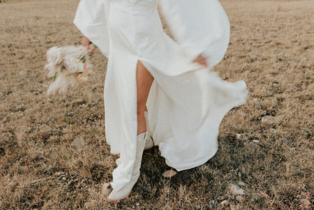 Bride's dress flowing in wind walking through field