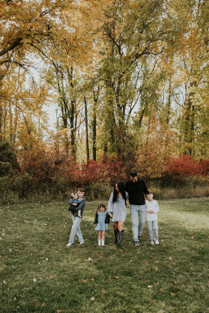 Family walking through a Montana field with mountains and golden fall trees in the background
